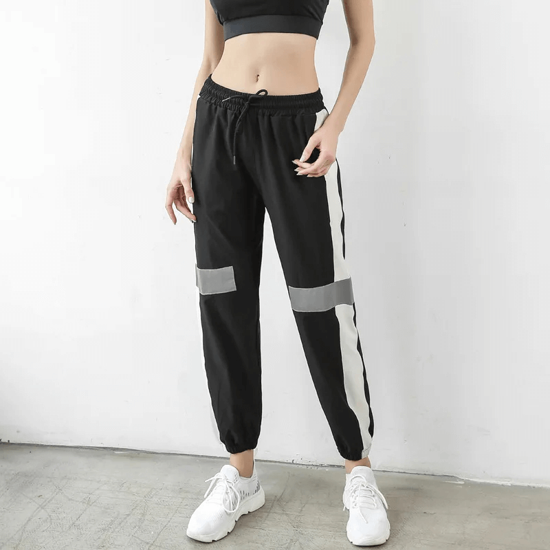 Person wearing stylish black and white athletic joggers with contrast stripes, showcasing modern active wear design and comfort.